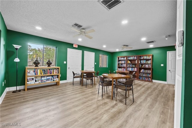 dining area with ceiling fan, light hardwood / wood-style flooring, and a textured ceiling