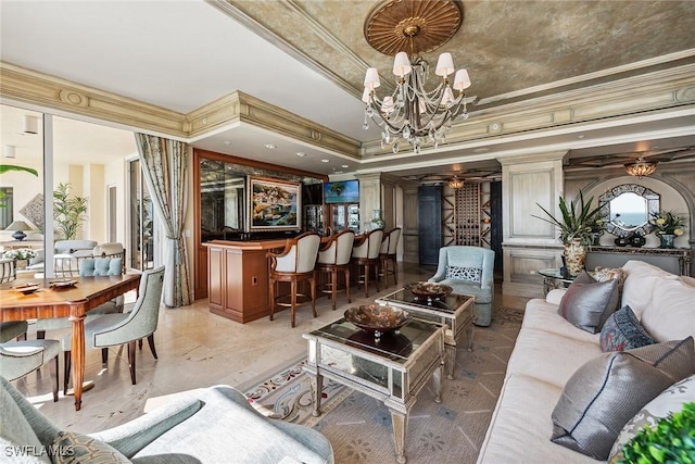 living room featuring crown molding, bar, decorative columns, a notable chandelier, and a tray ceiling