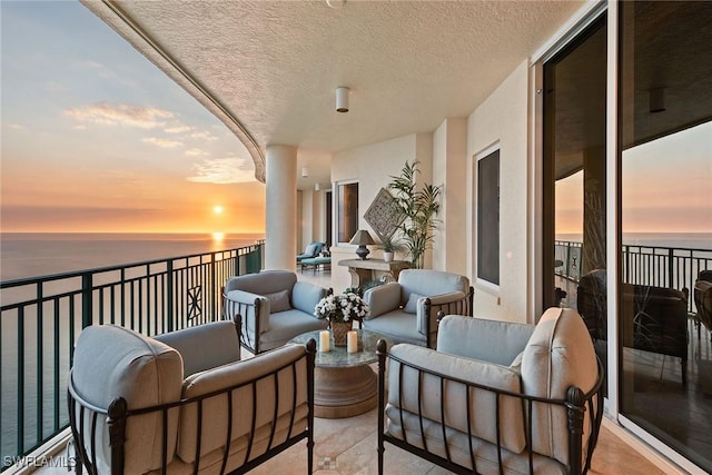 balcony at dusk featuring a water view