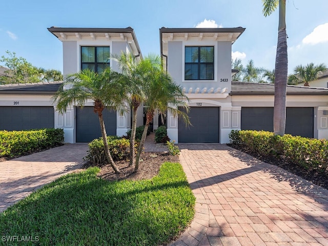 view of front of property featuring driveway, an attached garage, and stucco siding