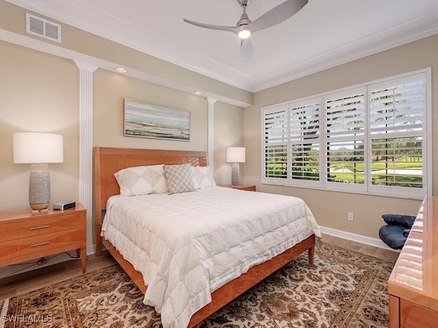 bedroom featuring wood finished floors, a ceiling fan, visible vents, baseboards, and ornamental molding