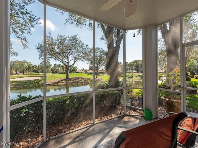 sunroom featuring a water view and a ceiling fan