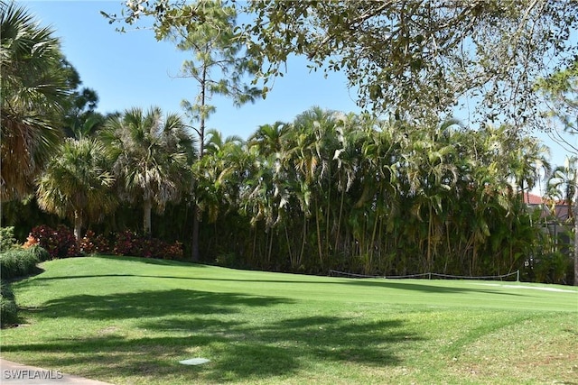 view of community with tennis court and a lawn