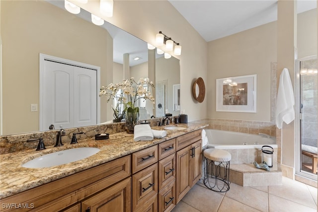 bathroom featuring tile patterned flooring, vanity, and tiled bath