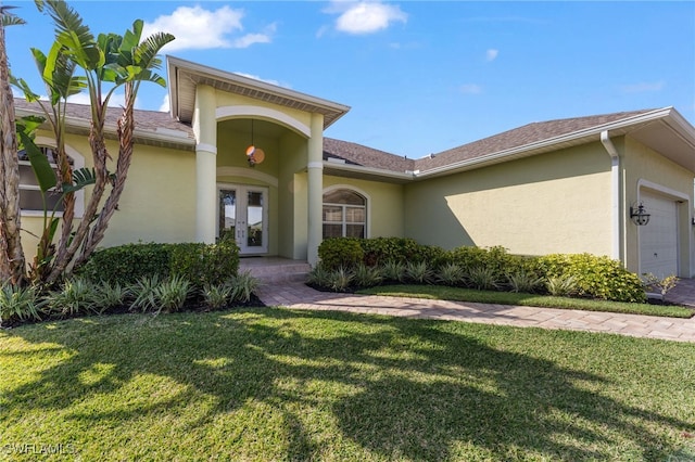 view of front of property with a garage, stucco siding, a front lawn, and french doors