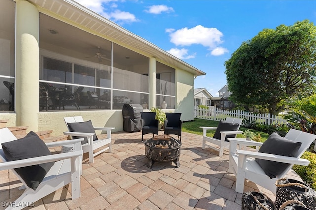 view of patio / terrace featuring an outdoor fire pit, fence, a sunroom, and a grill