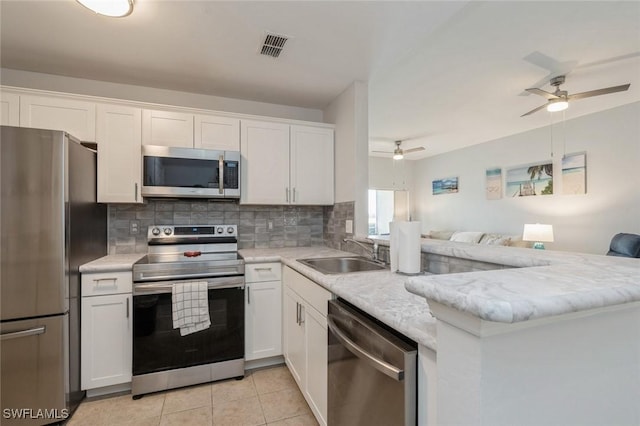 kitchen with appliances with stainless steel finishes, tasteful backsplash, sink, white cabinets, and kitchen peninsula