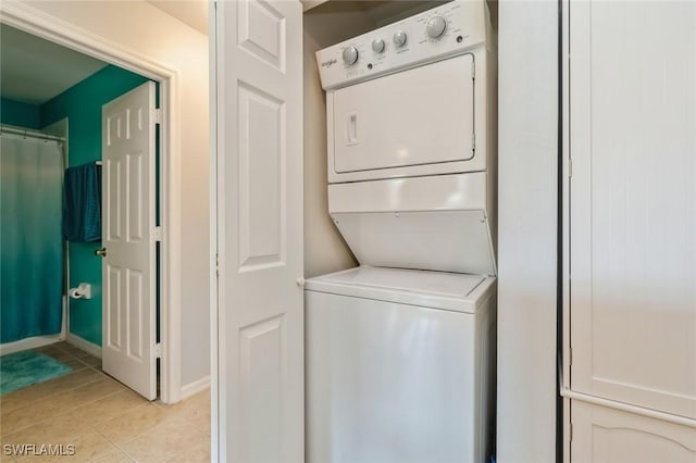 clothes washing area featuring light tile patterned floors and stacked washing maching and dryer