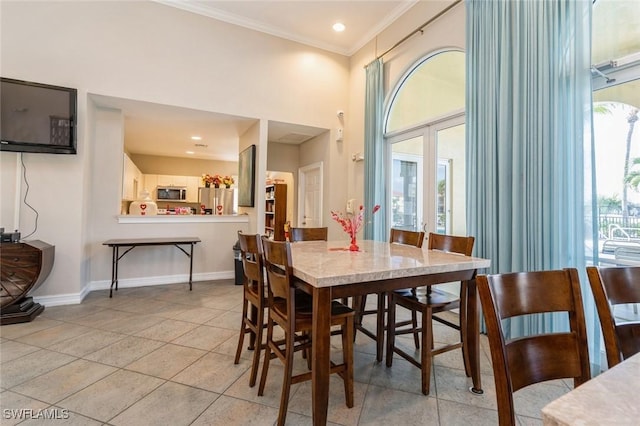 dining area with crown molding, light tile patterned floors, and french doors