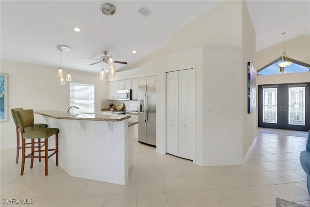 kitchen with visible vents, appliances with stainless steel finishes, a kitchen breakfast bar, french doors, and backsplash