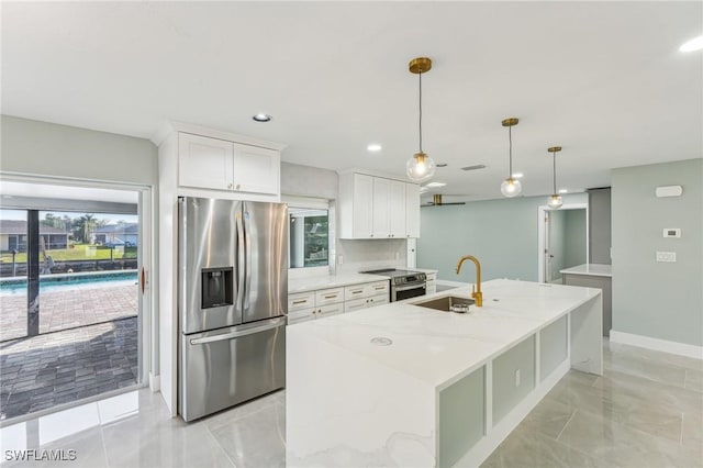 kitchen featuring stainless steel appliances, white cabinets, a sink, and an island with sink