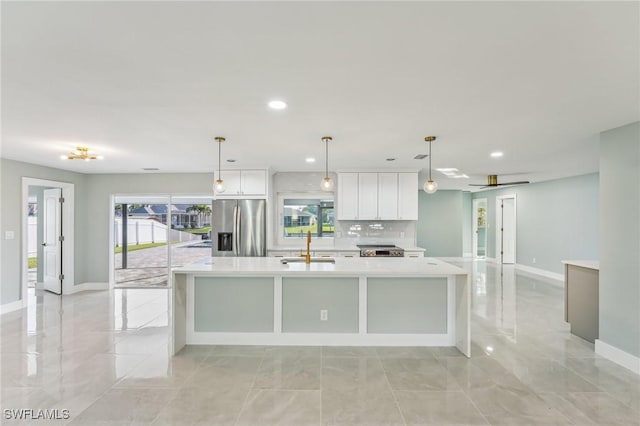 kitchen with a sink, white cabinets, light countertops, a large island, and stainless steel fridge with ice dispenser