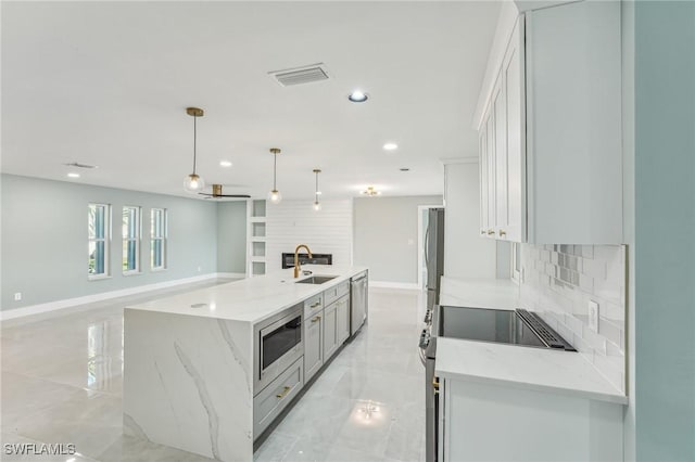 kitchen with visible vents, a large island, a sink, stainless steel appliances, and backsplash