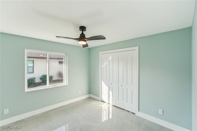 unfurnished bedroom with a closet, ceiling fan, baseboards, and light tile patterned floors