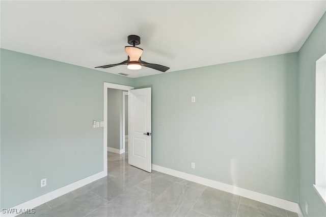 unfurnished room featuring ceiling fan and baseboards