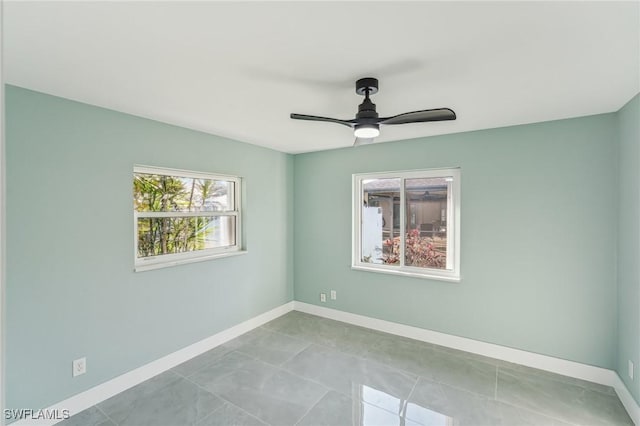 tiled spare room with ceiling fan and baseboards