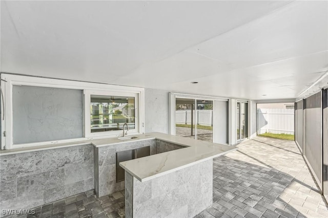 kitchen featuring a sink and light stone countertops