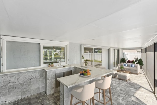 interior space featuring a sink, a breakfast bar area, and light stone countertops