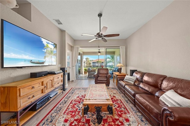 living room featuring a textured ceiling, wood-type flooring, and ceiling fan