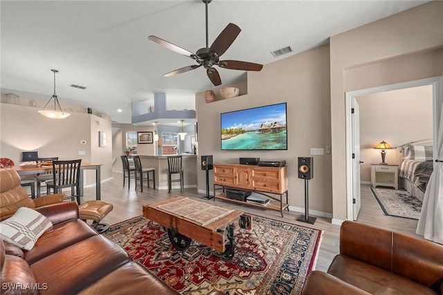 living room featuring ceiling fan, lofted ceiling, and light hardwood / wood-style floors