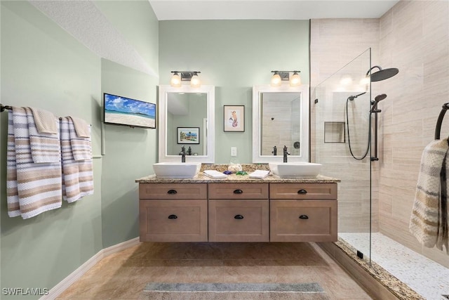 bathroom with tile patterned flooring, vanity, and a tile shower