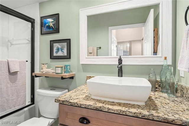 full bathroom with vanity, bath / shower combo with glass door, and toilet