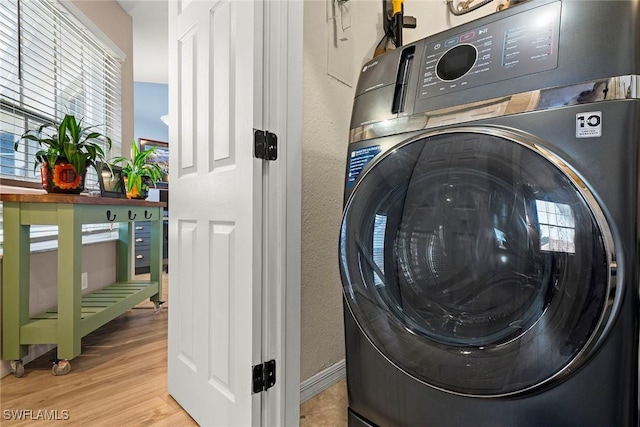 clothes washing area with washer / clothes dryer and light hardwood / wood-style floors