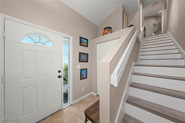 entrance foyer with plenty of natural light, vaulted ceiling, and light tile patterned floors