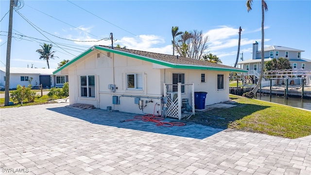 back of property with a yard, a patio area, and a water view