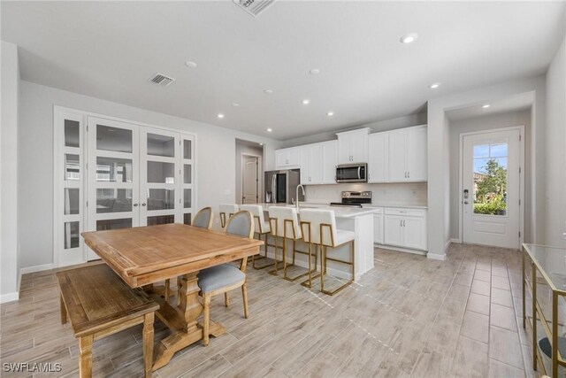 dining area with sink, light hardwood / wood-style floors, and french doors