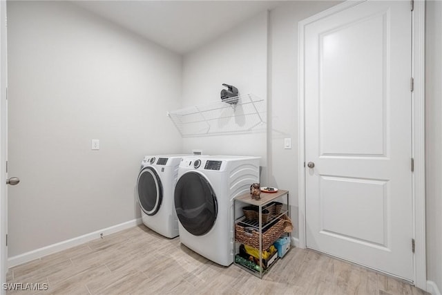 laundry room with washing machine and dryer and light hardwood / wood-style floors