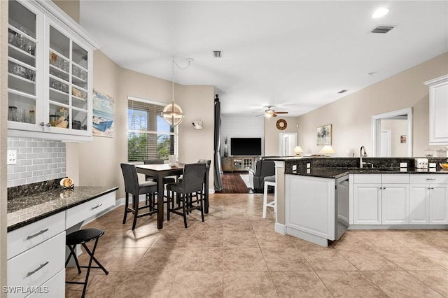 kitchen with hanging light fixtures, tasteful backsplash, dark stone countertops, and white cabinets