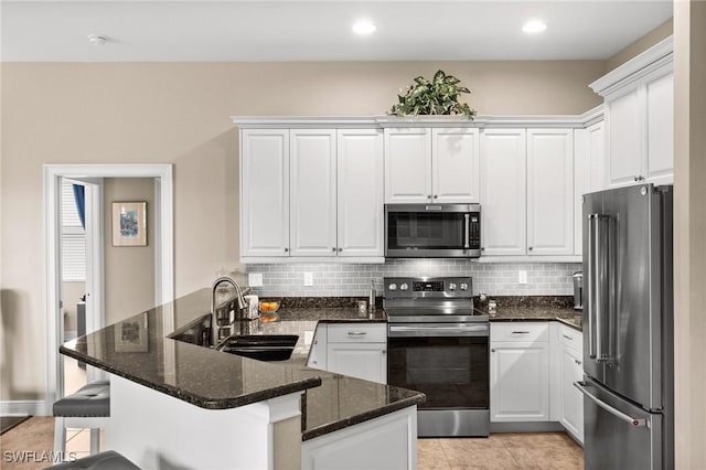 kitchen with sink, a kitchen breakfast bar, white cabinets, and appliances with stainless steel finishes