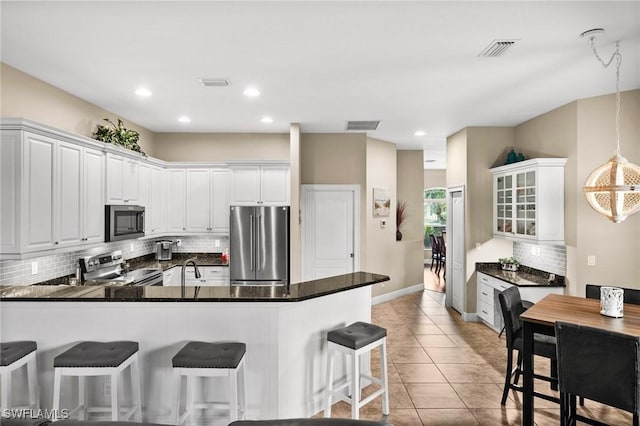 kitchen featuring stainless steel appliances, white cabinetry, a breakfast bar, and kitchen peninsula