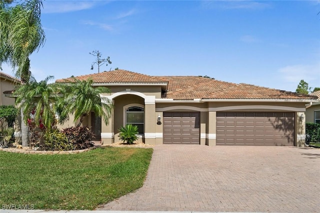 mediterranean / spanish house featuring a garage and a front lawn