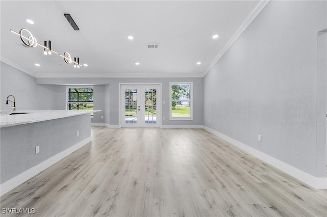 unfurnished living room featuring french doors, crown molding, sink, and light wood-type flooring