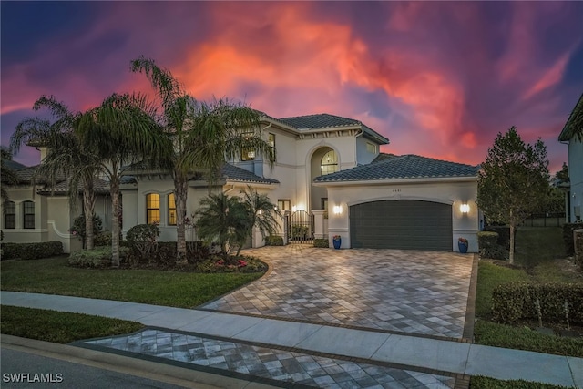 4641 Azalea Dr, Naples, FL 34119 - mediterranean / spanish-style house featuring stucco siding, an attached garage, a tiled roof, decorative driveway, and a yard