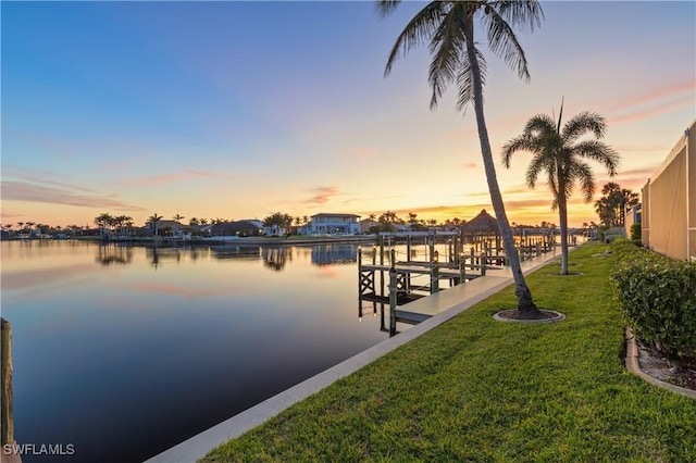 dock area with a lawn and a water view