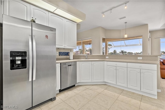 kitchen with decorative light fixtures, sink, white cabinets, light tile patterned floors, and stainless steel appliances