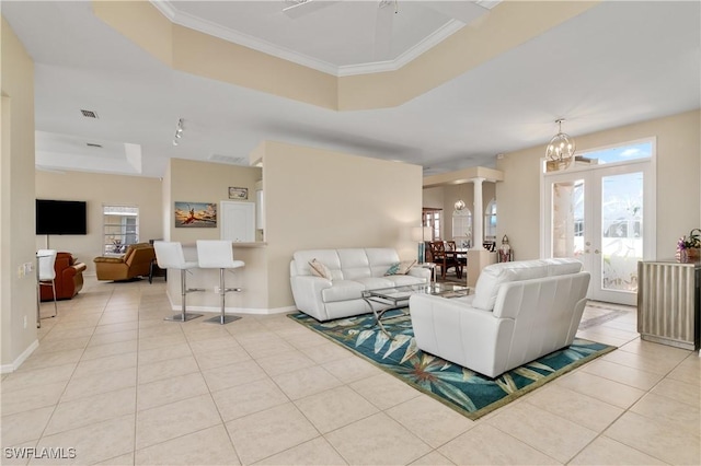 tiled living room with crown molding, a raised ceiling, and a healthy amount of sunlight