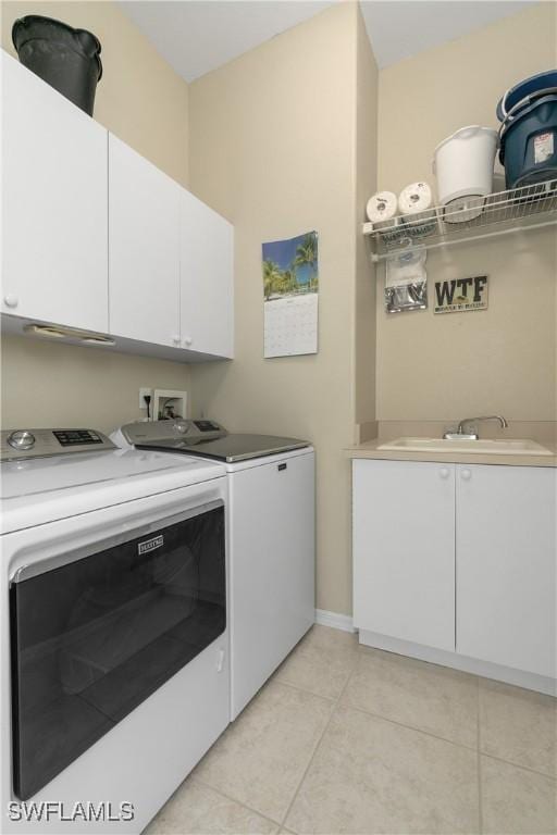 clothes washing area with cabinets, sink, light tile patterned floors, and washing machine and clothes dryer