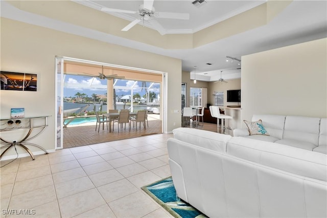 tiled living room featuring crown molding, a raised ceiling, and ceiling fan