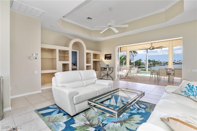 living room featuring light tile patterned floors, built in features, a raised ceiling, and a water view