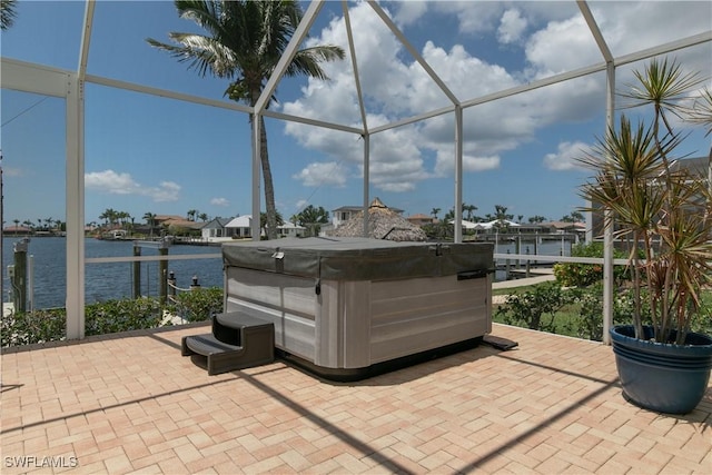 view of patio with a water view, a lanai, and a hot tub