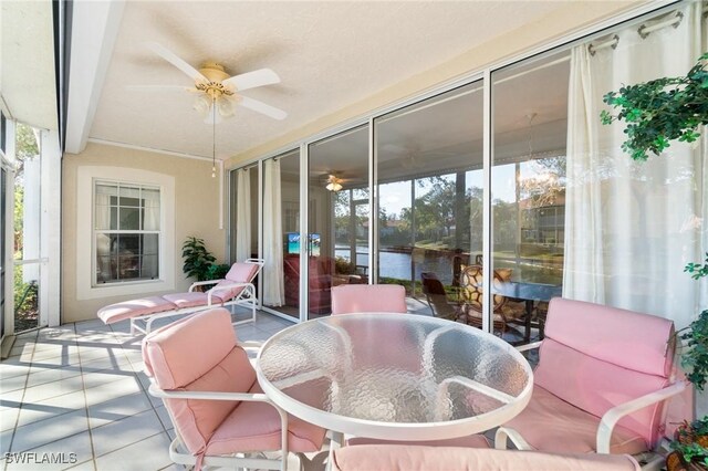sunroom with a water view, ceiling fan, and a healthy amount of sunlight