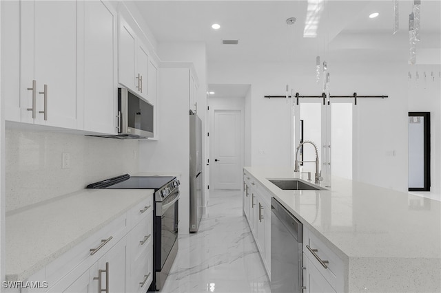 kitchen featuring appliances with stainless steel finishes, sink, a center island with sink, and white cabinets