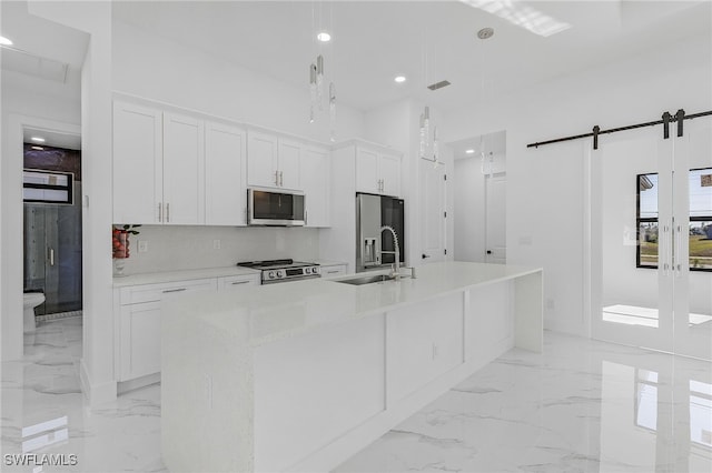 kitchen featuring appliances with stainless steel finishes, a center island with sink, and white cabinets