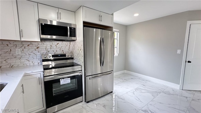 kitchen featuring backsplash, appliances with stainless steel finishes, light stone countertops, and white cabinets