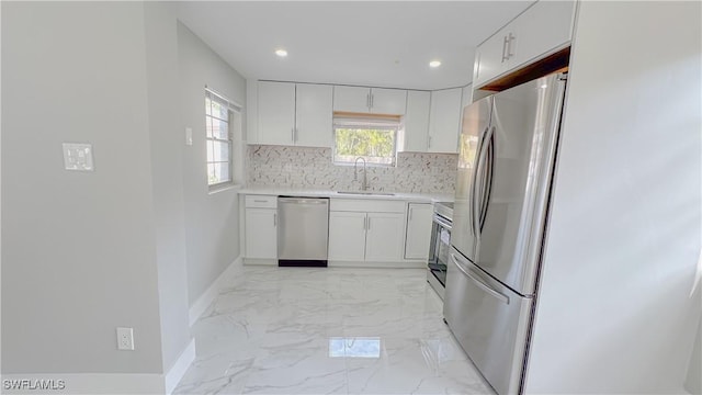 kitchen with stainless steel appliances, sink, white cabinets, and decorative backsplash