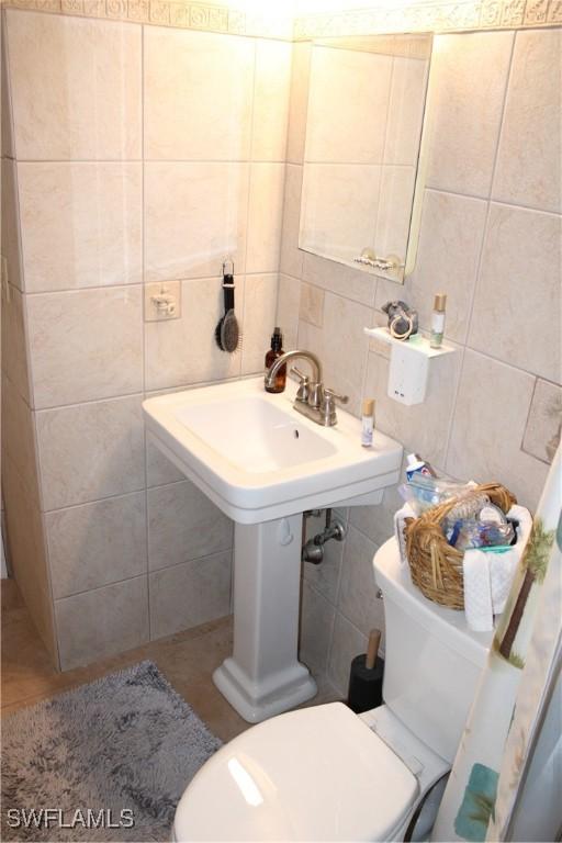 bathroom featuring tile walls, decorative backsplash, and toilet